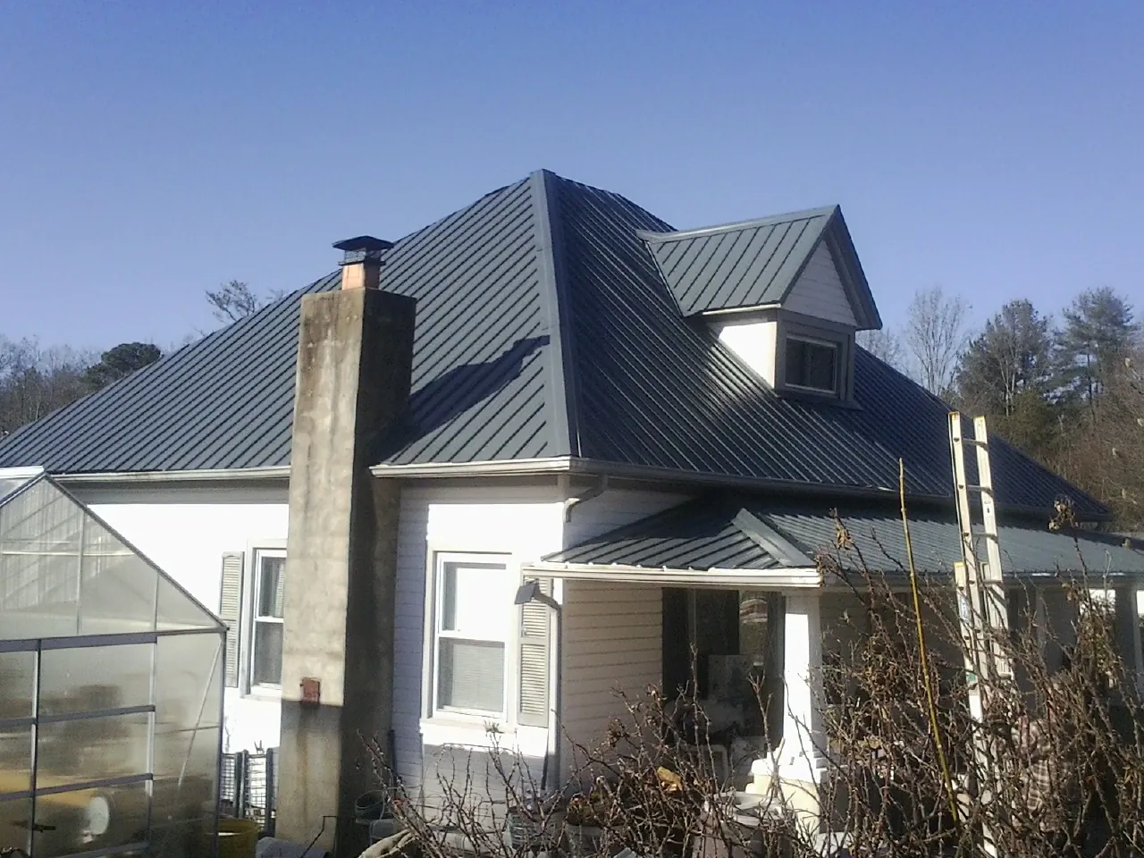 Dark blue standing seam metal roof on a white farmhouse with dormer — Slate & Tile Roof Repair by Roofing Brothers in Detroit
