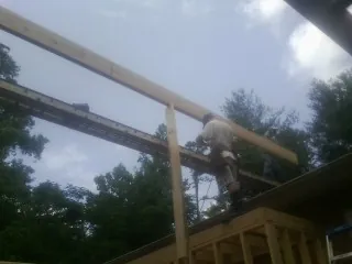 Carpenter setting a ridge beam over a new addition frame — Ice Dam Removal by Roofing Brothers in Detroit