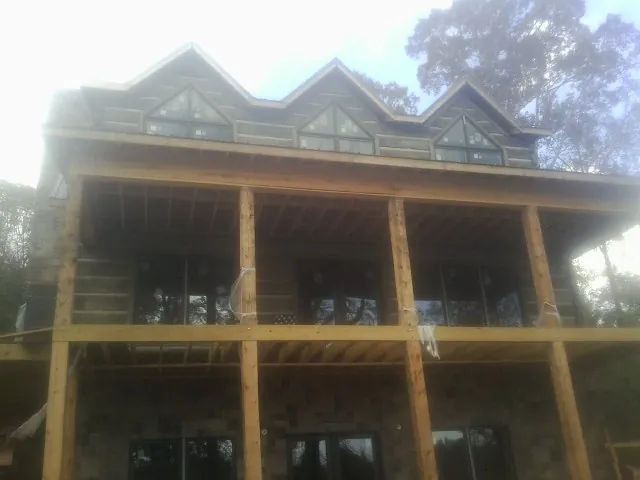 Dormers and porch framing on a large log home under construction — Roof Coating work by our crew in Detroit