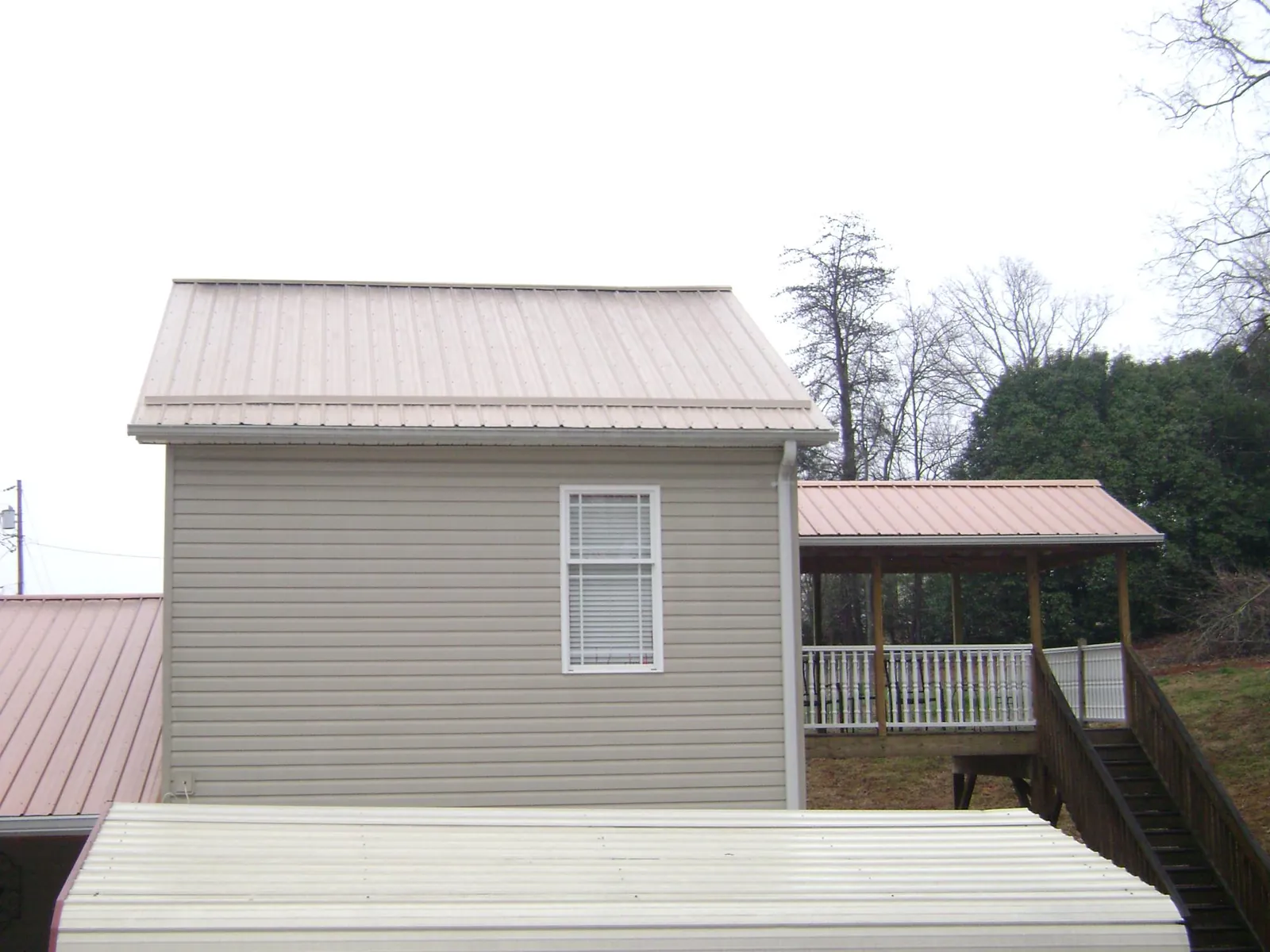 Tan metal roofs on a two story addition and attached porch, from a Roof Replacement job in Detroit