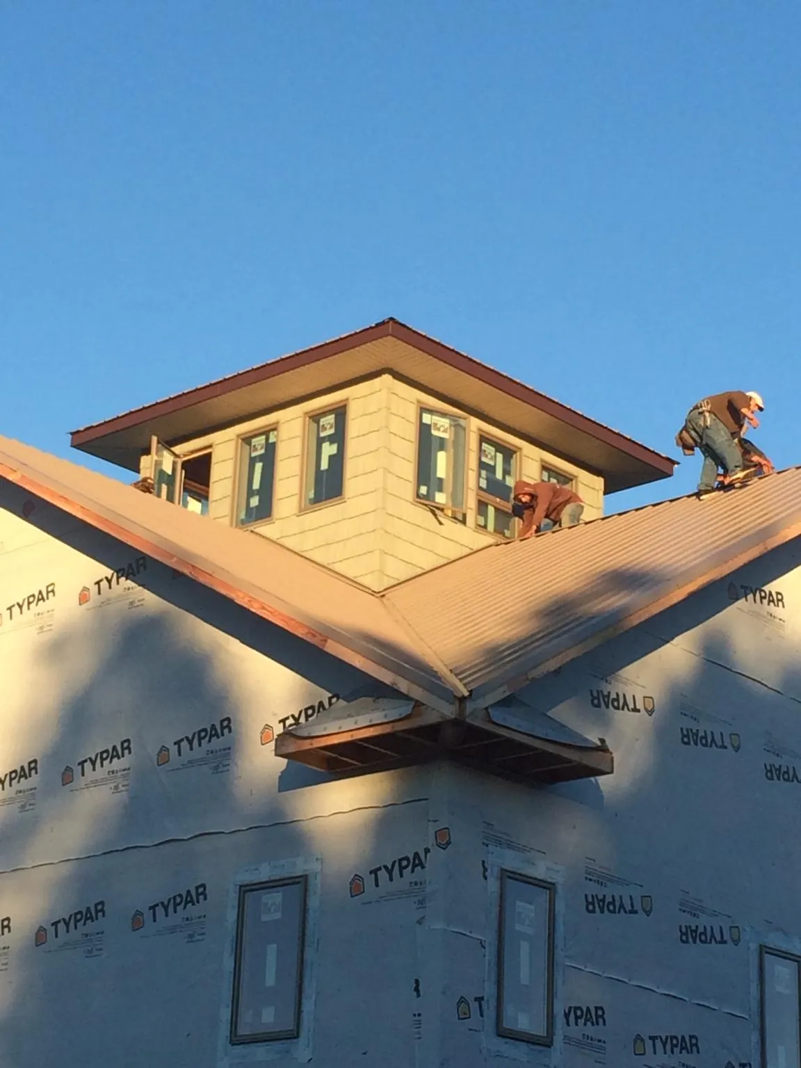 Roofers working around a rooftop cupola on a new metal roof at sunset — Roof Waterproofing in Detroit by Roofing Brothers